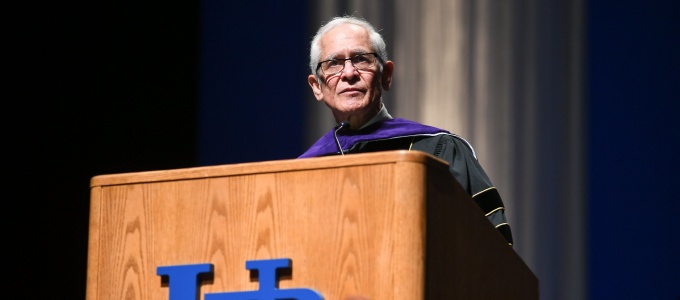 man wearing glasses speaking at a podium. 