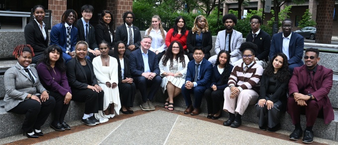 Group portrait of approximately two dozen Discover Law Scholars and program leaders seated and standing in an outdoor plaza on the University at Buffalo campus.