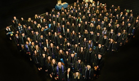 Law students standing looking up at the camera, dressed in graduation regalia. 