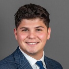 man wearing suit and tie, smiling. 