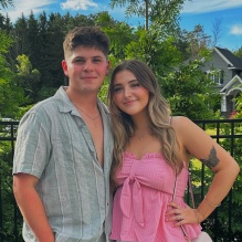 youn man and woman standing outside in a garden, smiling. 