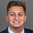 man wearing suit and tie, smiling. 