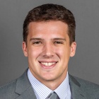 man smiling, wearing suit and tie. 