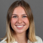 woman smiling, wearing white blouse. 