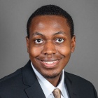 young man smiling, wearing suit and tie. 