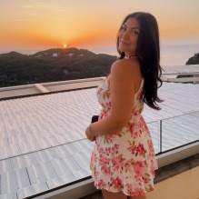 Young woman standing on an outdoor patio during sunset.