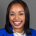 woman smiling, wearing blue jacket. 