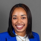 woman smiling, wearing blue jacket. 