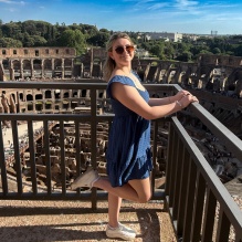 Young woman standing on an overlook of a Roman era structure.