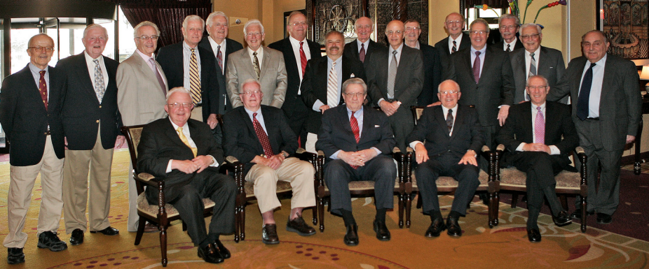 a group of men sitting inside a big room posing for a photo.