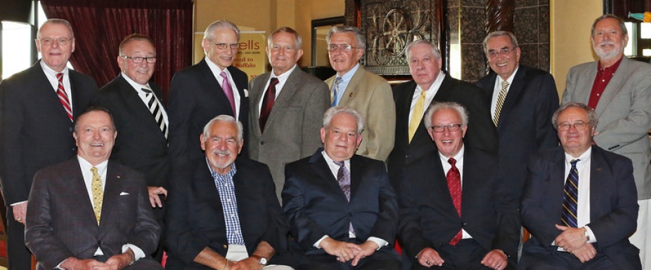 a group of men sitting inside a big room posing for a photo.