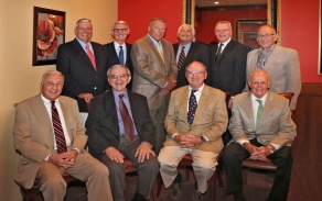 Group of men sitting and standing together for their photo. 