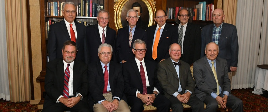 group of alumni inside a large room, posing for their group photo. 