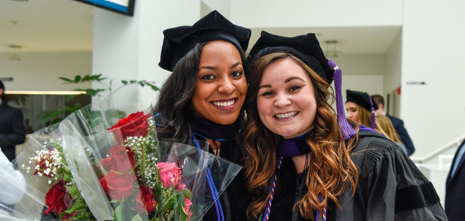 photo of two graduates following their commencement ceremony.