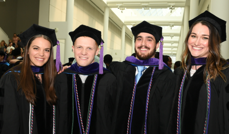 a group of recent law school graduates, smiling, wearing graduation regalia. 