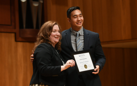 two people on stage, one holding an award they'd just received. 