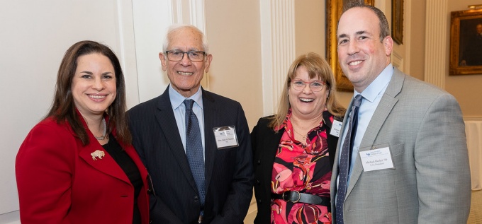 Group of people standing together for a photo, smiling, in a banquet room. 