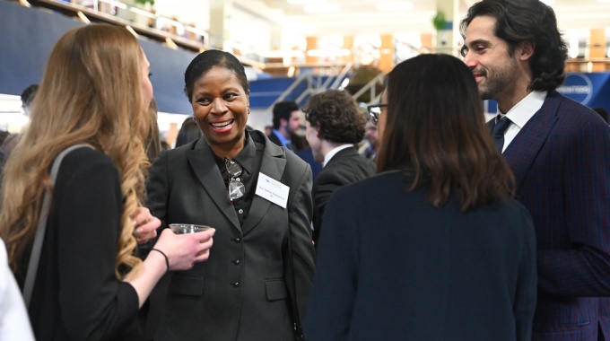 Group of people at an event, standing, smiling and talking. 