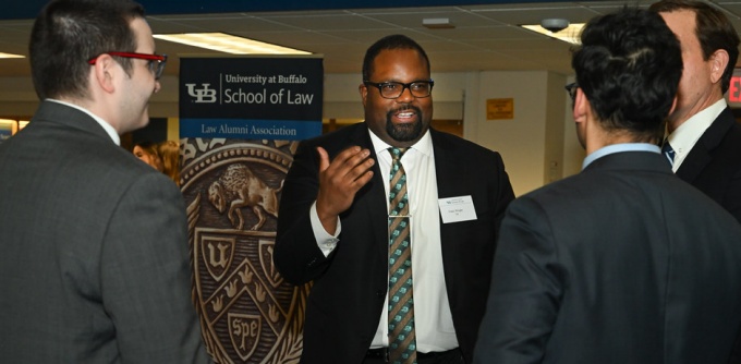 Group of men standing, talking at an event. 