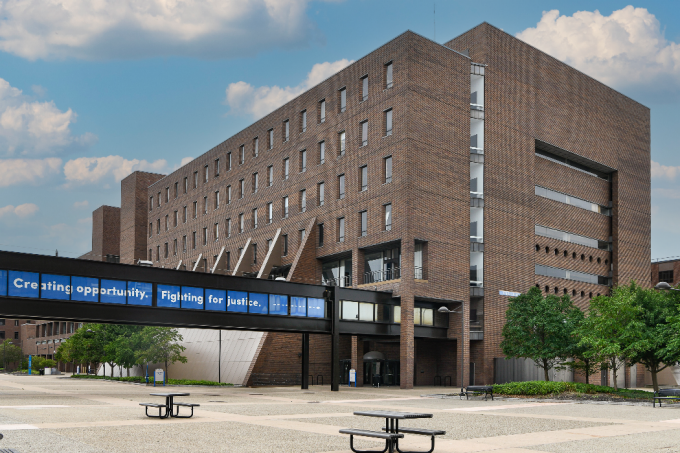 Exterior image of O'Brian Hall, North Campus with the bridge text "Creating opportunity. Fighting for justice". 