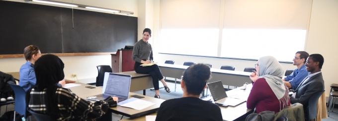 students in a classroom with professor harrington sitting in the center of the room. 