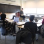 students in a classroom with professor harrington sitting in the center of the room. 