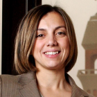 Woman wearing brown jacket, smiling. 