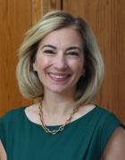 Bartholomew wearing green top, gold necklace, smiling.