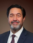 Melber wearing buisiness suit, tie, smiling.