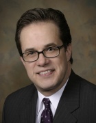 Franczyk wearing buisiness suit, tie, smiling.