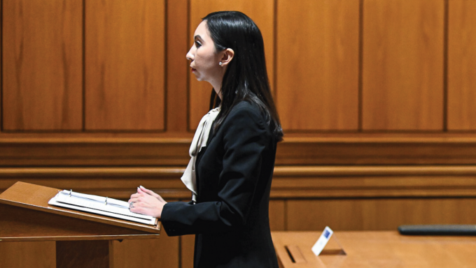 Woman in a courtroom standing at a podium.