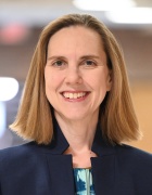 Scharf wearing black jacket, smiling.