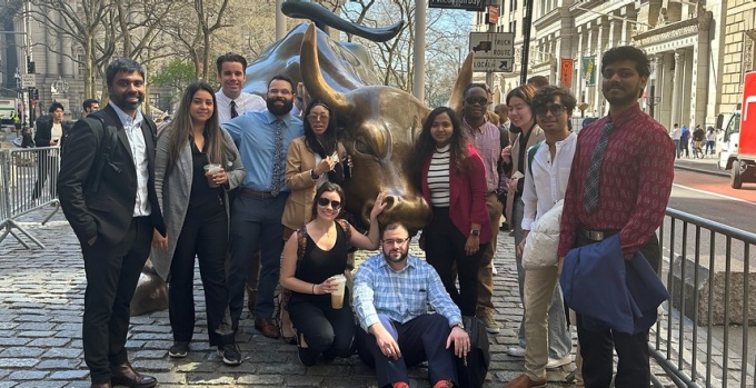 group of students standing aroundn the wall street bronze bull. 