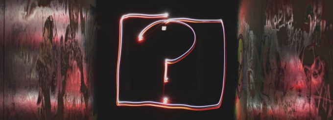 neon red question mark with black background.
