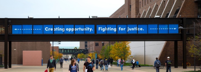 photo of UB North Campus promenate with O'Brian Hall on the right and walkway sign that reads creating opporutnity fighting for justice.
