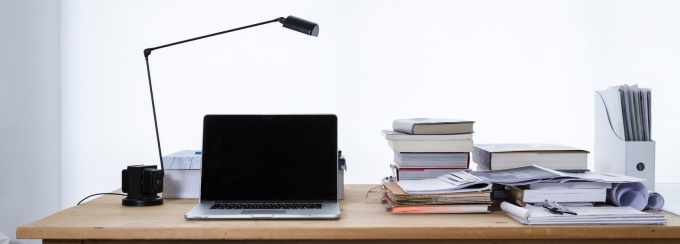 photo of a desk with a lamp and laptop and several books.