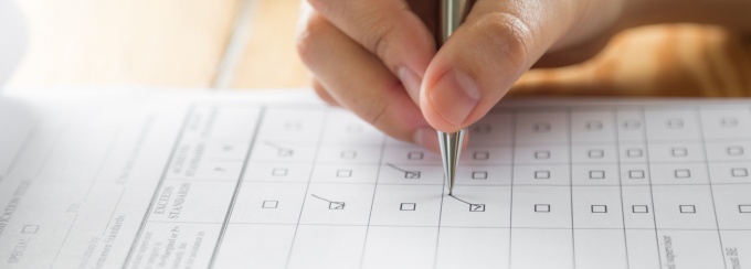 a hand checking off a box with a pen on a paper checklist.