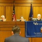 Picture of a student attorney at a podium in a courtroom speaking to a panel of judges. 