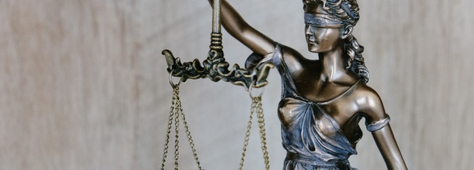 statue of scales of justice, a woman with a blindfold holding a scale up.