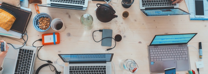 photo of laptops on a desk and hands pointing at the laptop screens.