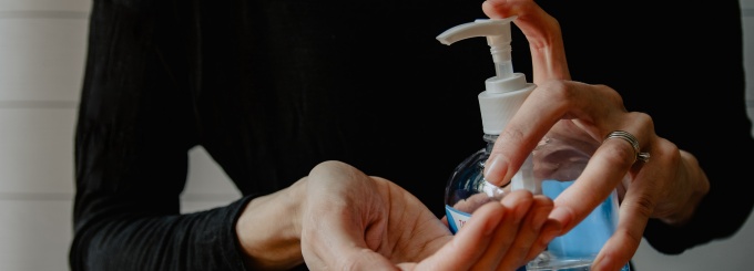 hands pumping hand sanitizer on other hand.