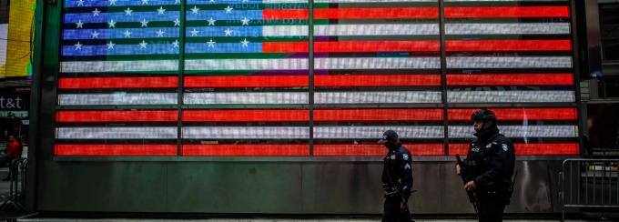 Police walking in front of american flag neon sign.