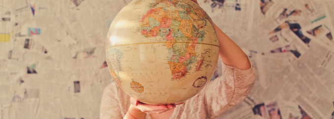 Photo of a person holding a globe in front of their face.