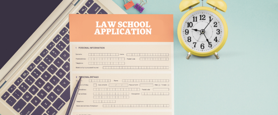 Laptop with a paper law school application and alarm clock. 