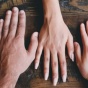 Hands laid across a wooden table. 