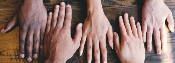 Hands laying across a wooden table. 