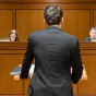 In a courtroom, man standing in front of a judges bench, addressing the judges. 