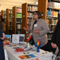 People attending career fair in the law library, standing at a table, talking. 