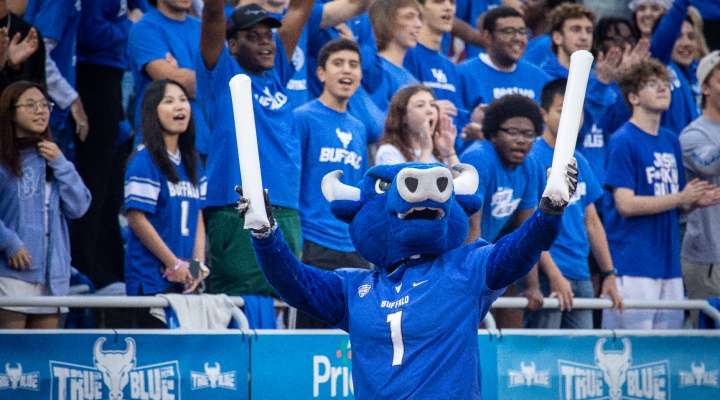 UB mascot, Victor E. Bull, cheering with students at a football game. 