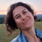 Woman outside in a field, smiling. 